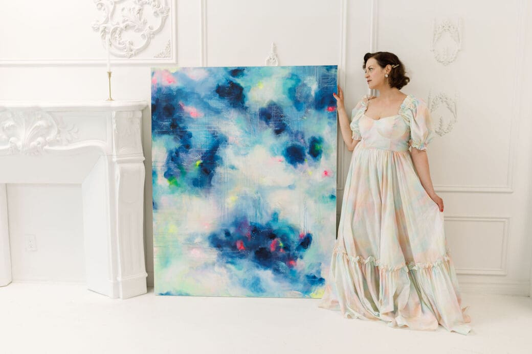 Artist Sarena Miller stands beside her large abstract painting called "Dancing Motes"